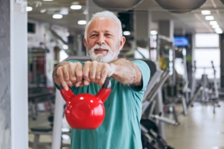 Older White Man Lifts Kettlebell at Gym