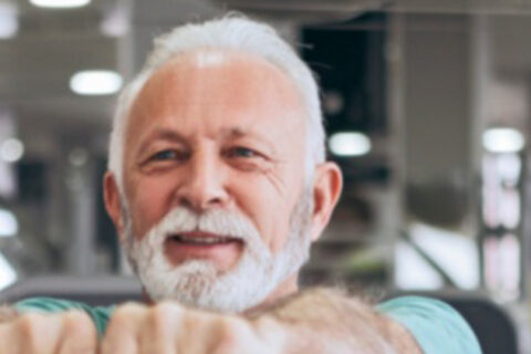 Older White Man Lifts Kettlebell at Gym